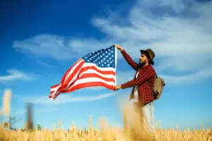 Homme tenant un drapeau américain dans un champ