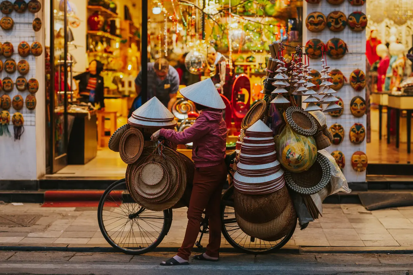 Assurance voyage Vietnam Marchand a velo avec chapeau conique au Vietnam